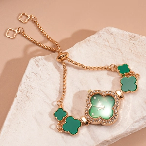 Detail of clover bracelet watch with green dial and rhinestones on stone background
