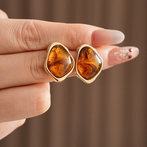 Detailed close-up of vintage geometric earrings with amber resin in a golden metal frame
