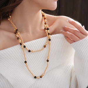 Double-layered tiger eye and gold bead necklace worn on a white sweater