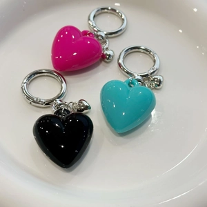 Detailed view of heart-shaped resin keychains in rose red, black, and turquoise colors