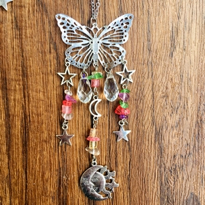 Detail of butterfly suncatcher with crystal ball and moon pendants on a wooden background