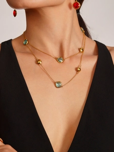 Gros plan sur le collier double épaisseur en acier plaqué or avec pierres rouges et bleues