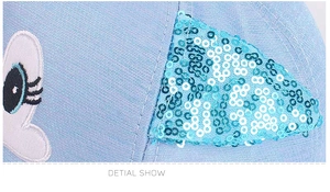 Dettaglio del cappellino azzurro con orecchie di paillettes e grandi occhi ricamati