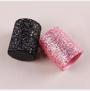 Detail of pink and black glitter makeup brush holders on a light beige background