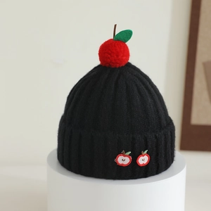 Detail of black knit hat with apple embroidery and red pom-pom top for kids