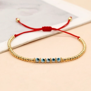 Détail du bracelet œil protecteur avec cordon rouge, perles dorées et nœud coulissant