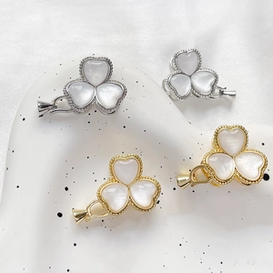 Macro detail of gold and silver clover jewelry clasps with white mother of pearl inlay