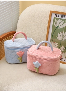 Detail of corduroy makeup bags with tulip embroidery and quilted texture on soft fabric