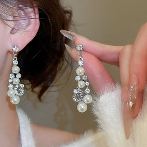 Vue détaillée de boucles d'oreilles pendantes en perles et strass portées par un mannequin