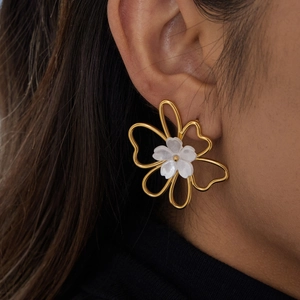 Elegant gold flower stud earrings with white pearl center on female model ear