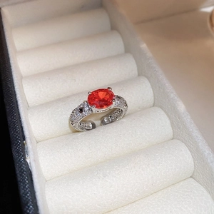 Macro view of silver ring featuring an oval orange gemstone and pavé set small diamonds