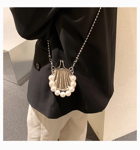Kleine silberne Muschelumhängetasche mit Perlenbesatz und Kettenriemen am Modell