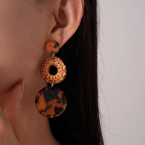 Detail of bohemian rattan circle drop earrings with tortoiseshell resin and fringe accents