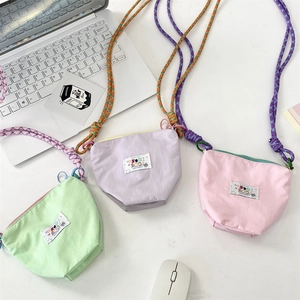 Close-up of candy-colored canvas crossbody phone bags with woven rope straps and embroidery