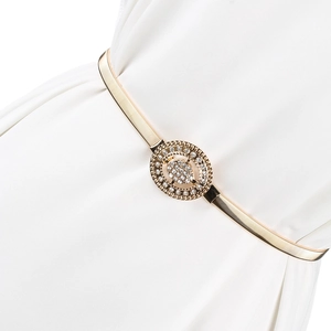Détail d'une ceinture élastique dorée avec une boucle ovale ornée de strass brillants