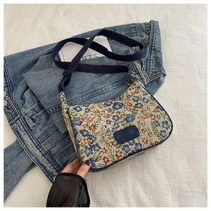 Detail of floral jacquard embroidery pattern and navy leather logo tag on the shoulder bag