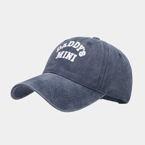 Detail view of washed denim texture and white DADDY'S MINI print on the baseball cap