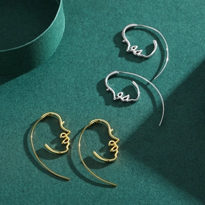 Abstract line art face earrings in gold and silver S925 sterling silver on green texture