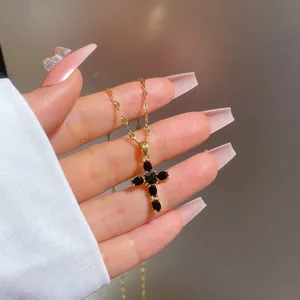 Close-up of titanium steel gold necklace with black zircon cross pendant on a hand