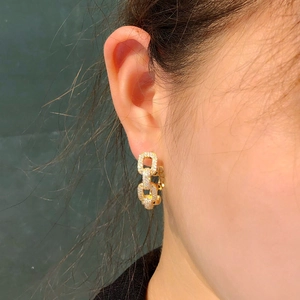 Elegant gold chain-link hoop earrings with sparkling crystals shown on a female model
