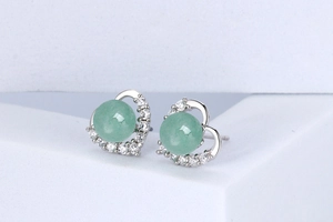 Macro shot of silver heart-shaped stud earrings with green jadeite stone and small diamonds