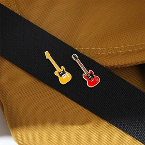 Electric guitar enamel brooches in red and yellow pinned to a black canvas strap