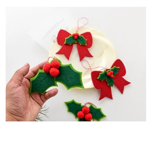 Detail of handmade Christmas felt ornaments with red bows and green leaf berries