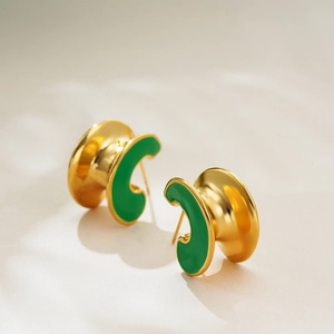 Detailed close-up of 18K gold-plated C-shaped earrings with green enamel finish