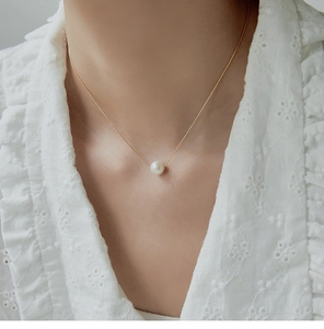 Close-up of a single round white pearl necklace with a delicate 18K gold-plated chain