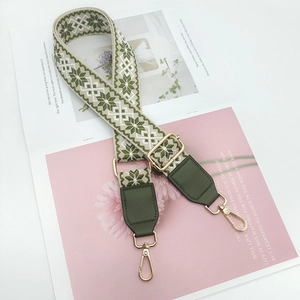 Close-up of adjustable woven bag strap with green snowflake pattern and gold metal hooks
