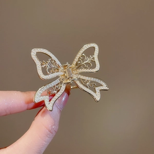 Detail of a golden metal butterfly hair claw clip with white pearls and hollow pattern
