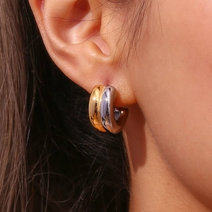 Detail of three-tone C-shaped hoop earrings featuring polished gold, silver and matte finish