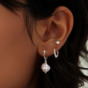 Close-up of stacked s925 silver earrings with turquoise, baroque pearl and zircon studs