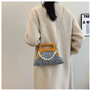 Detail of grey tweed evening bag with wooden handle, pearl chain and gold strap