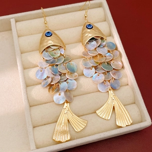 Close-up of vintage fish earrings with evil eye detail and iridescent shell scales