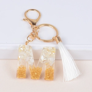Fashionable resin letter M keychain with gold foil flakes and a white silk tassel detail