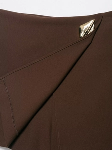 Detail of coffee brown fabric texture with a decorative irregular gold metal piece