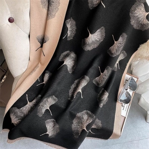 Close-up of double-sided cashmere shawl with golden ginkgo leaf pattern and elegant tassels