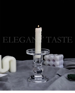 Macro shot of glass candle holder with ribbed pillar design and lit white wax candle