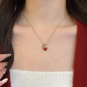Close-up of 18k gold plated necklace with a red heart pendant and colorful bead accents