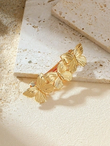Detailed view of three golden metal butterflies on a hair clip over a textured stone base