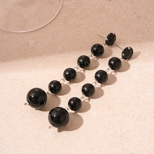 Macro detail of elegant black beaded drop earrings with geometric faceted studs
