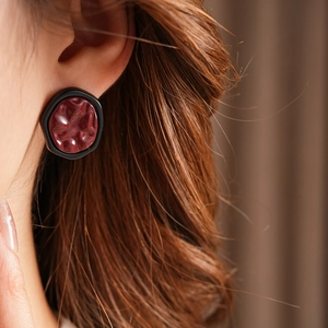 Close-up of vintage geometric wine red earrings with textured finish on a model