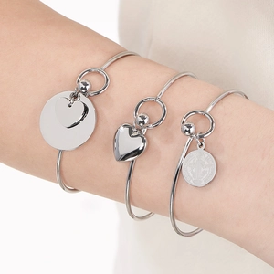 Close-up of polished stainless steel heart charms and medals on fashion bracelets