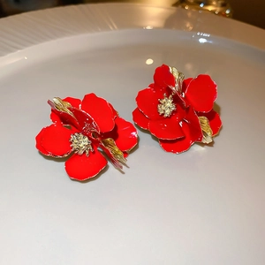 Detailed macro view of vibrant red flower earrings with elegant gold-rimmed petal details