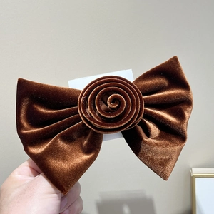 Gros plan d'une pince à cheveux en velours marron foncé avec détail de fleur de rose douce