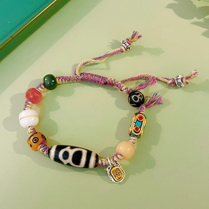 Macro detail of ethnic Dzi bead bracelet with woven cord and colorful painted beads