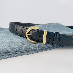 Vintage crocodile pattern leather belt in black with gold buckle on blue jeans
