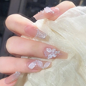 Macro shot of long coffin fake nails with 3D butterflies, camellias, and shiny glitter