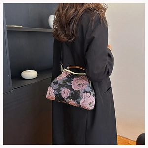 Detail of vintage floral fabric handbag featuring a wooden handle and metallic clasp